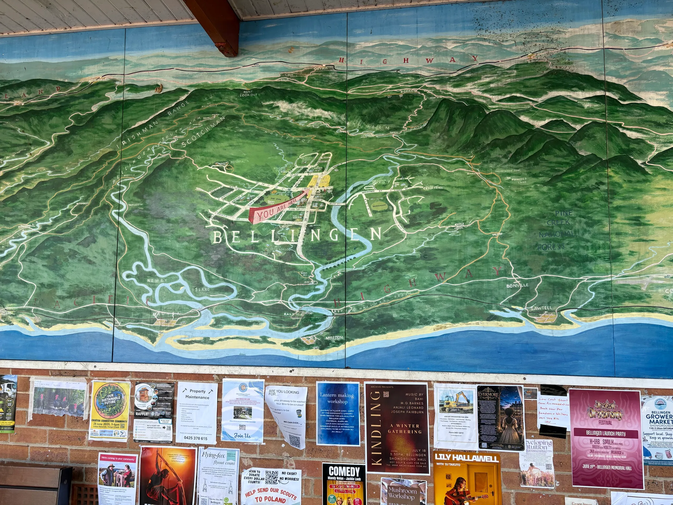 A painted map mural of the Bellingen valley above a community board
