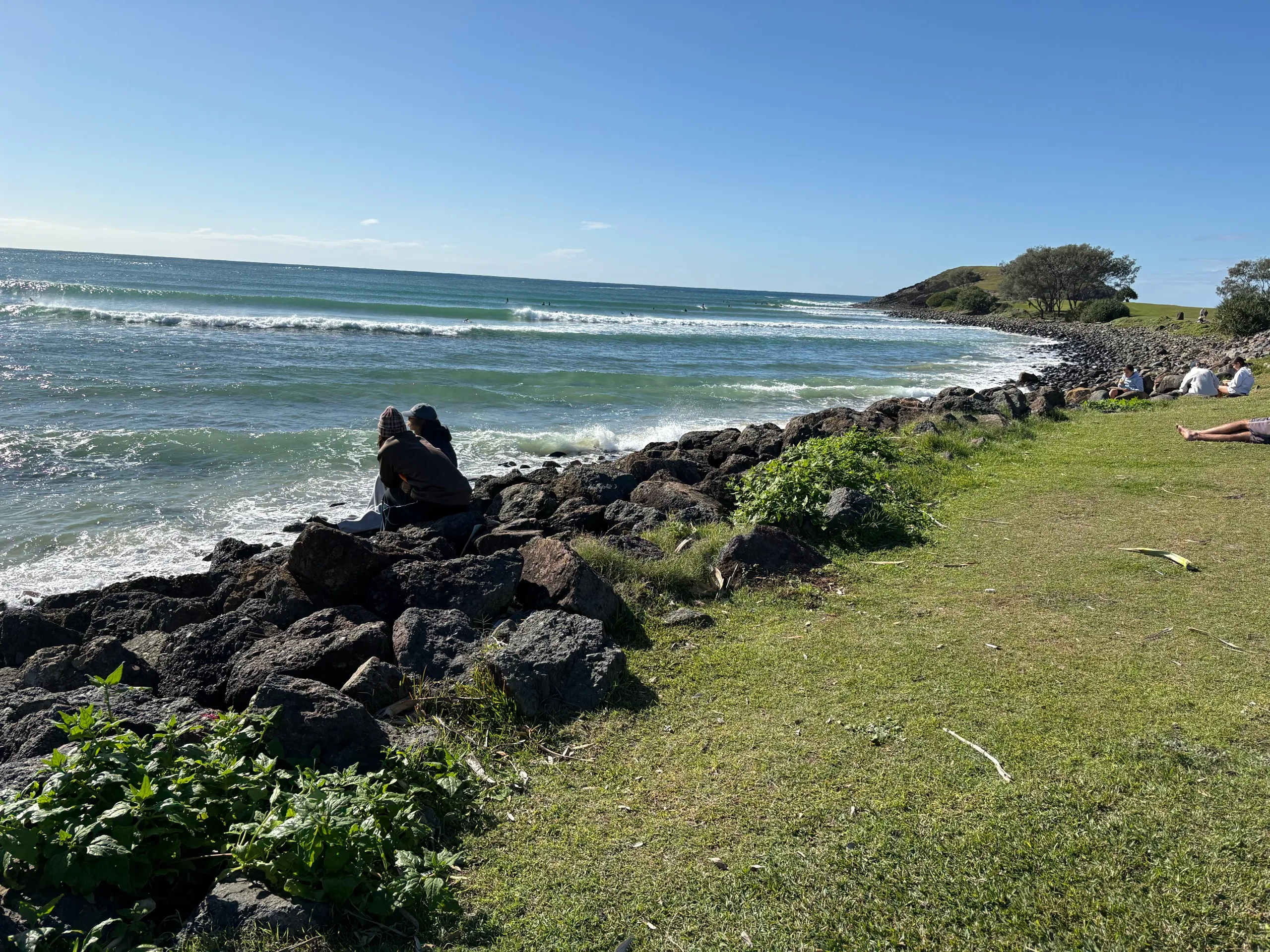 Two people sitting on the rocks watching the surf at Crescent Head