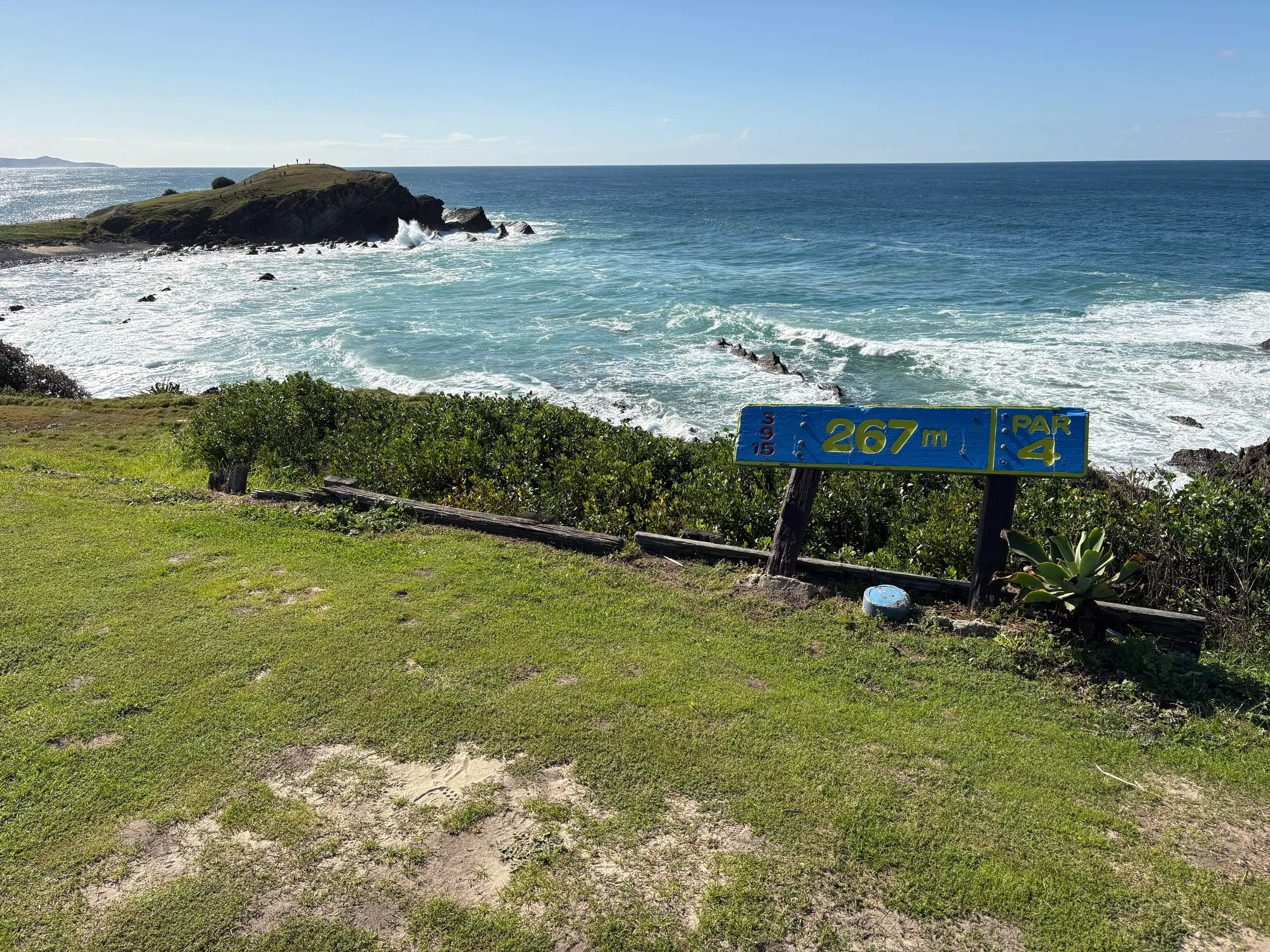A golf hole marker on the headland above the surf and rocks at Crescent Head