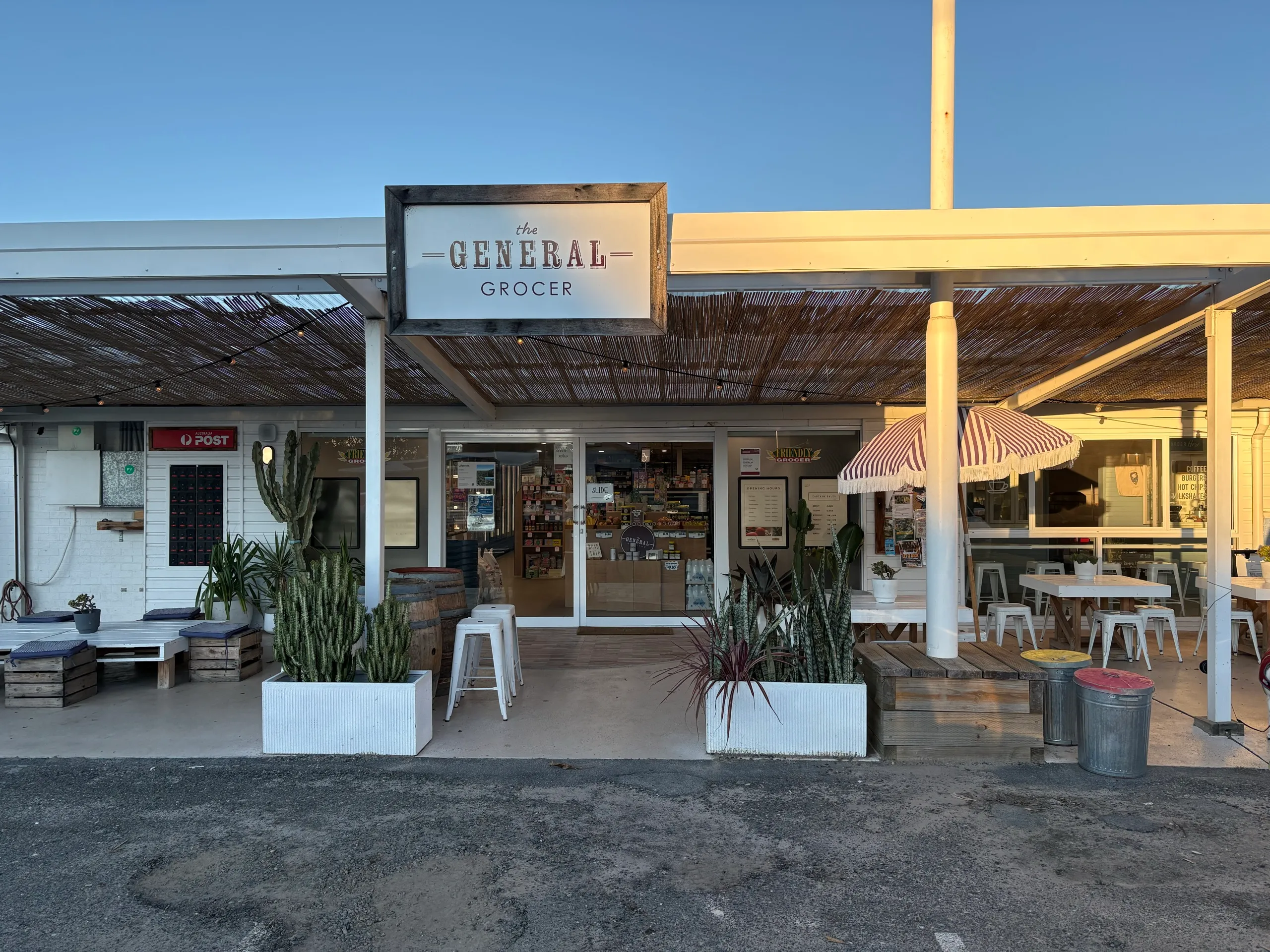 The General Store at Hat Head, a beachside grocer with outdoor seating and an Australia Post sign