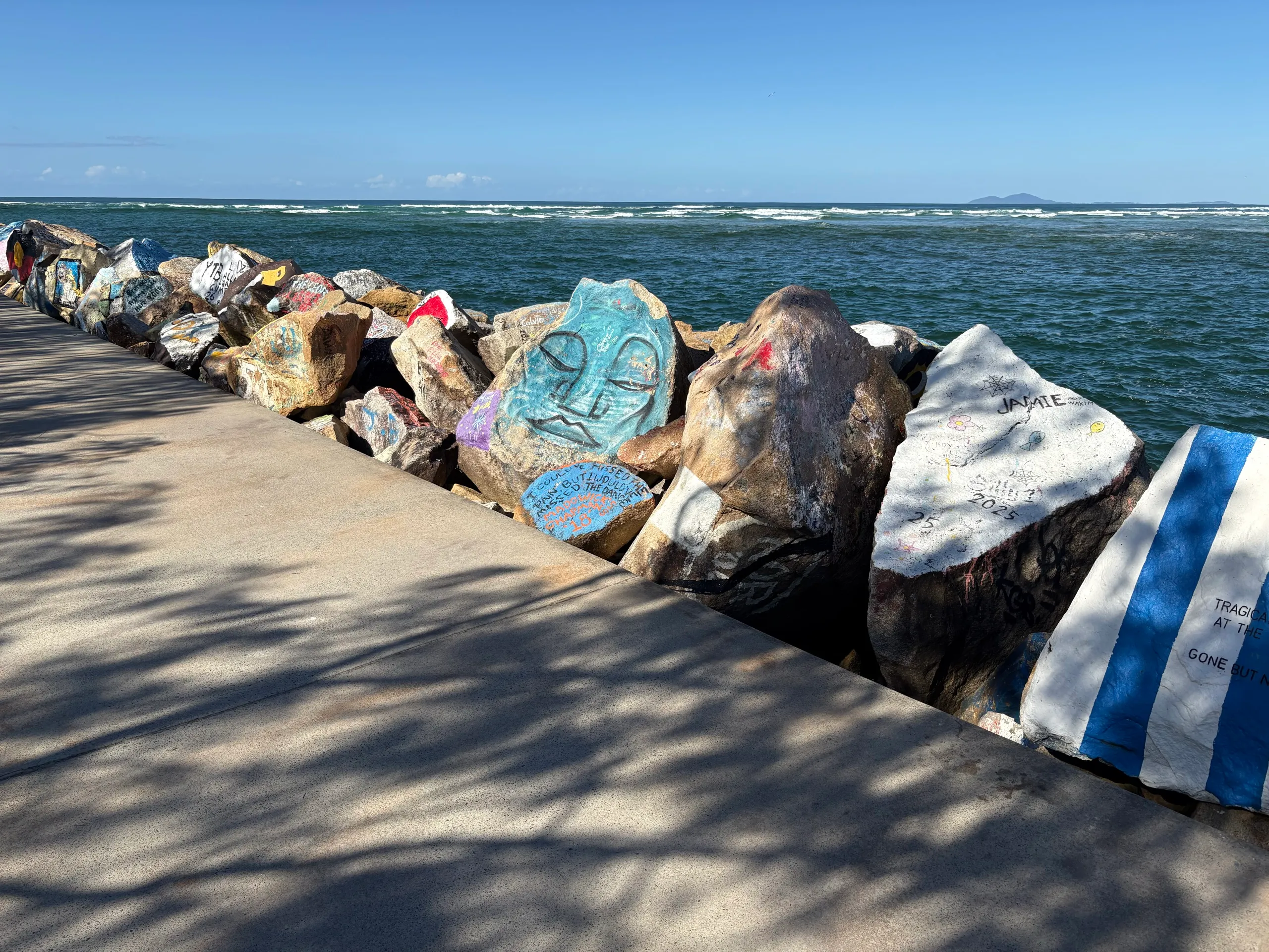 Close-up of painted message rocks along the V-Wall at Nambucca Heads