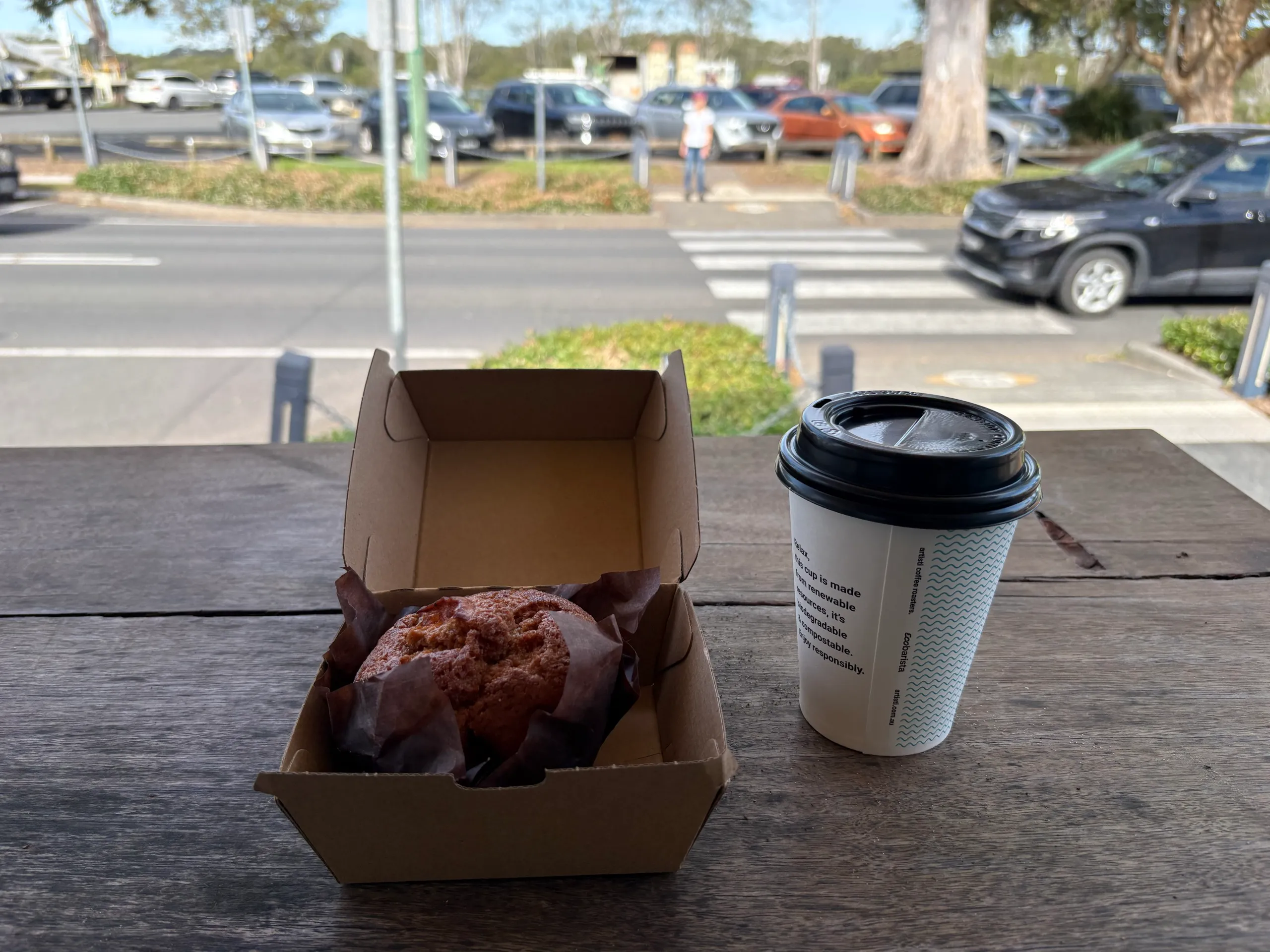 A takeaway coffee and a muffin on a table near the North Haven shops
