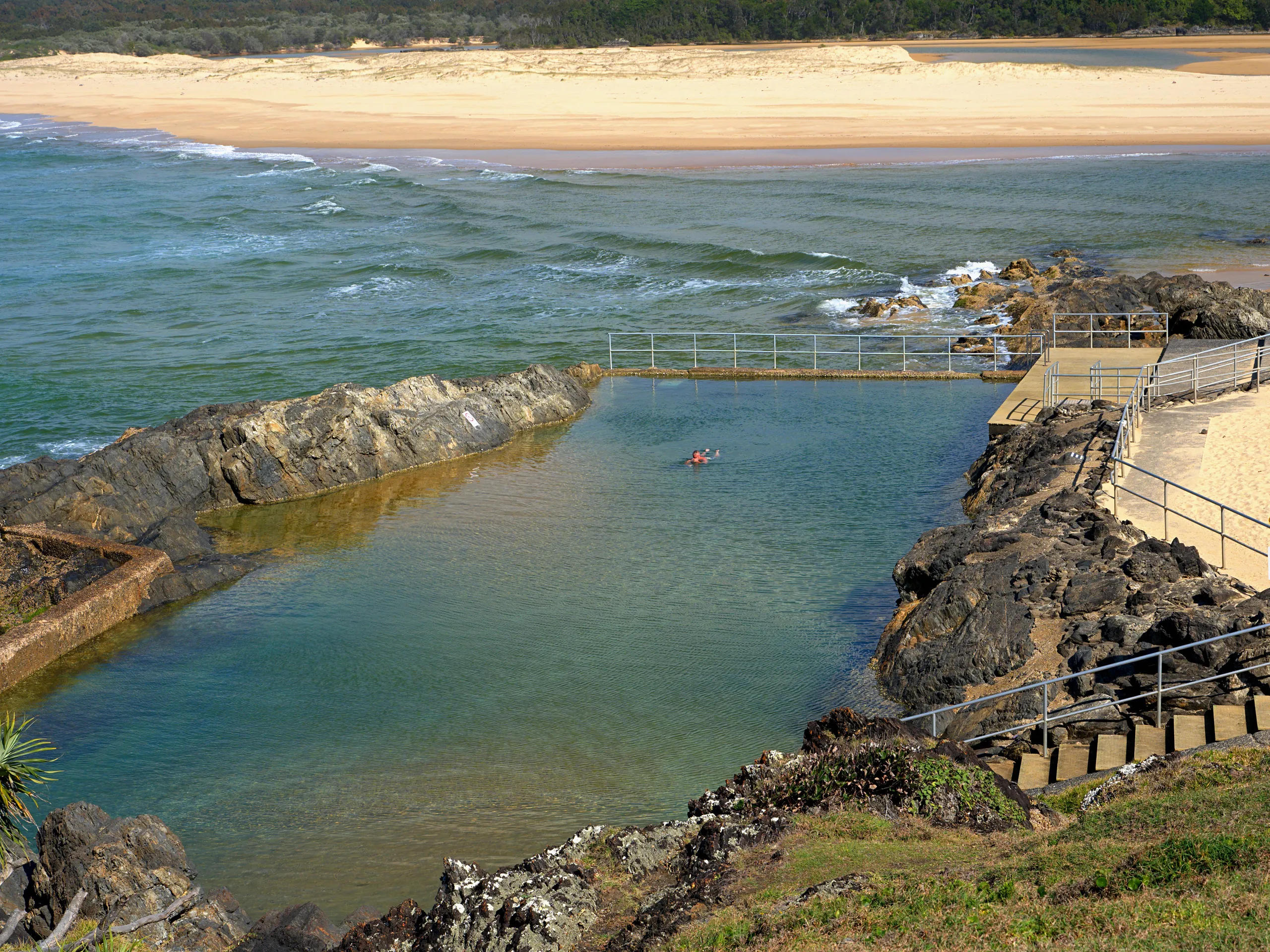 A swimmer in Sawtell Memorial Rock Pool, an ocean pool cut into the rocks below Bonville Headland