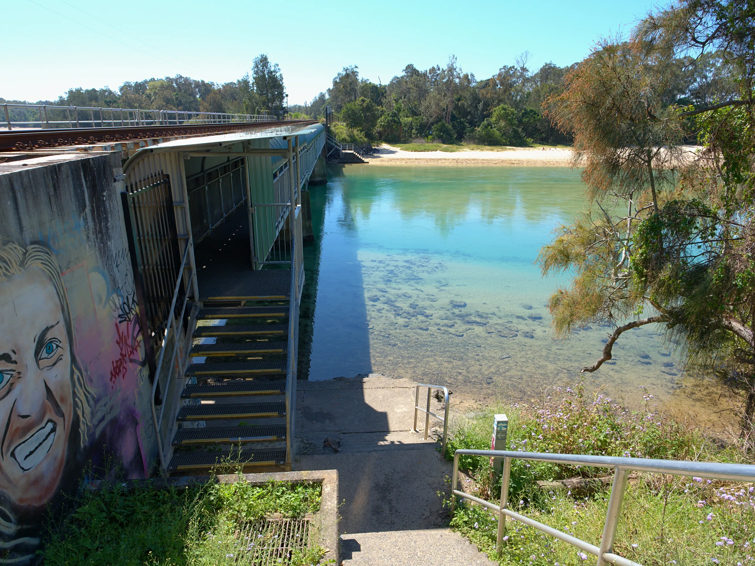 Steps leading down to the clear water of Boambee Creek beside the railway bridge