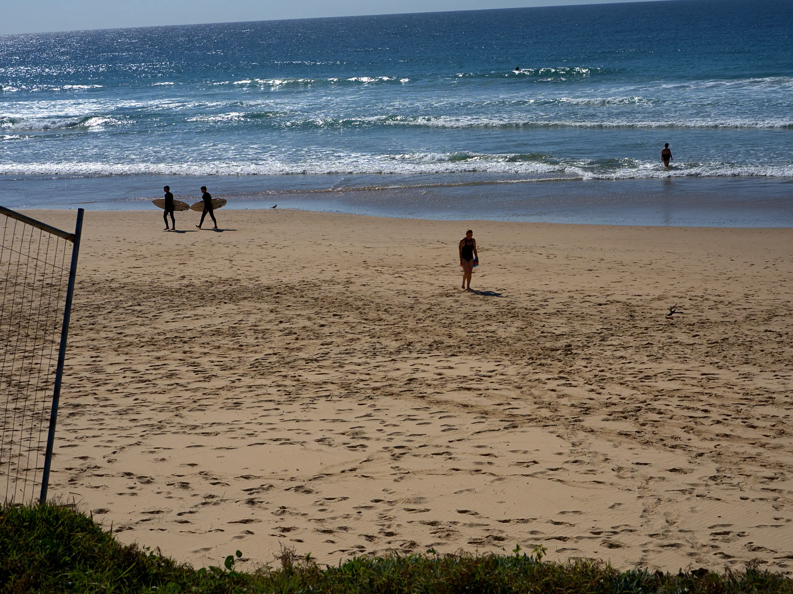 Surfers carrying their boards across the sand at Sawtell Main Beach