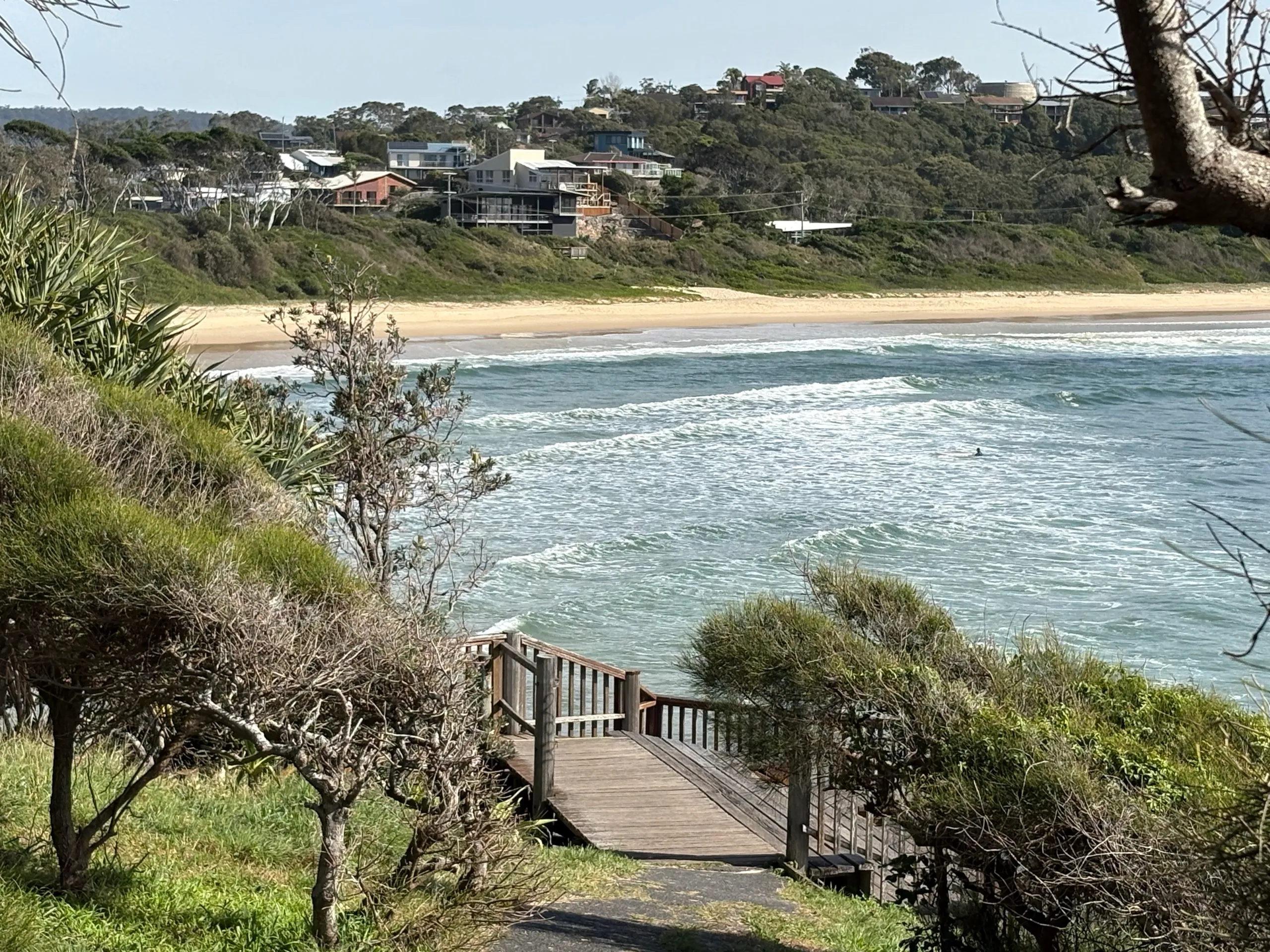 Timber steps leading down to the beach at Scotts Head with lines of swell rolling in