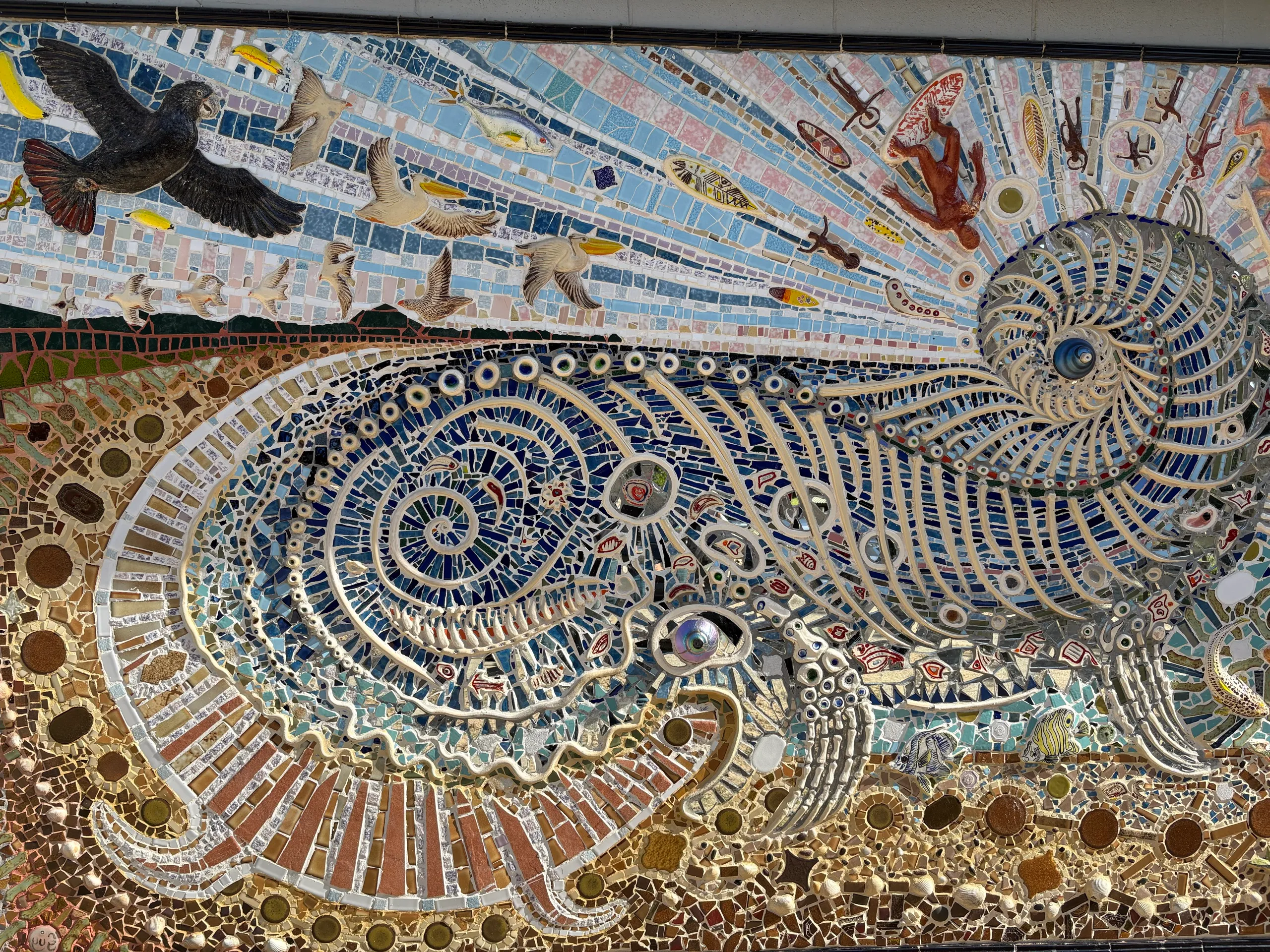 A detailed tiled mosaic mural of a shell and seabirds on the foreshore at Scotts Head