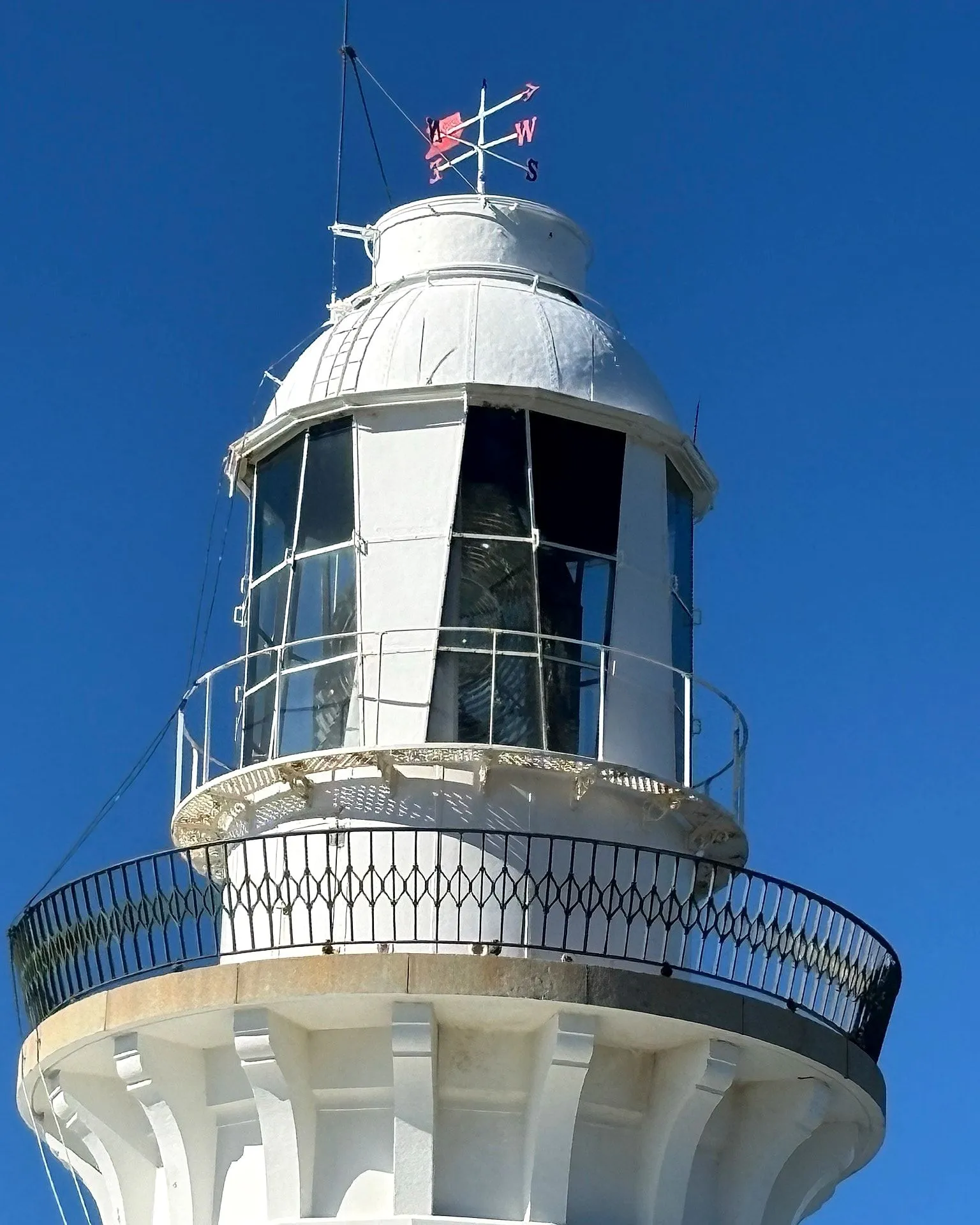 The lantern room of Smoky Cape Lighthouse with its weathervane and original lens