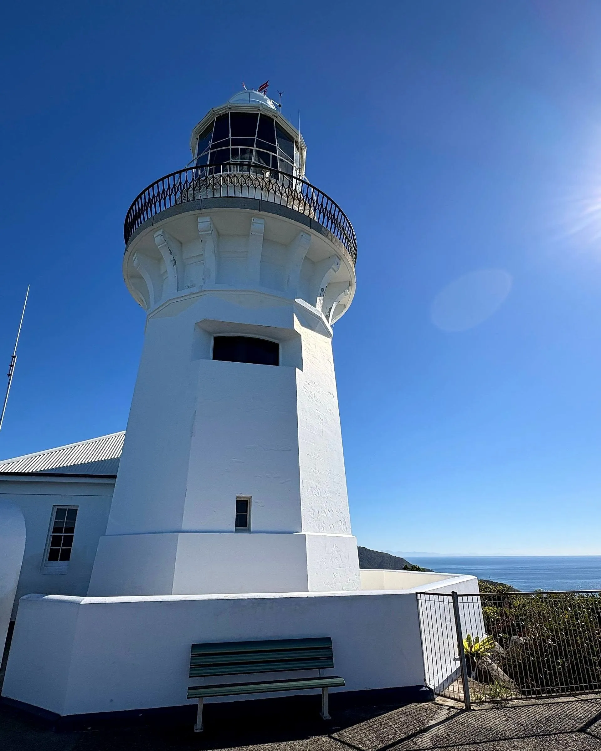 Smoky Cape Lighthouse from its base, white against a deep blue winter sky